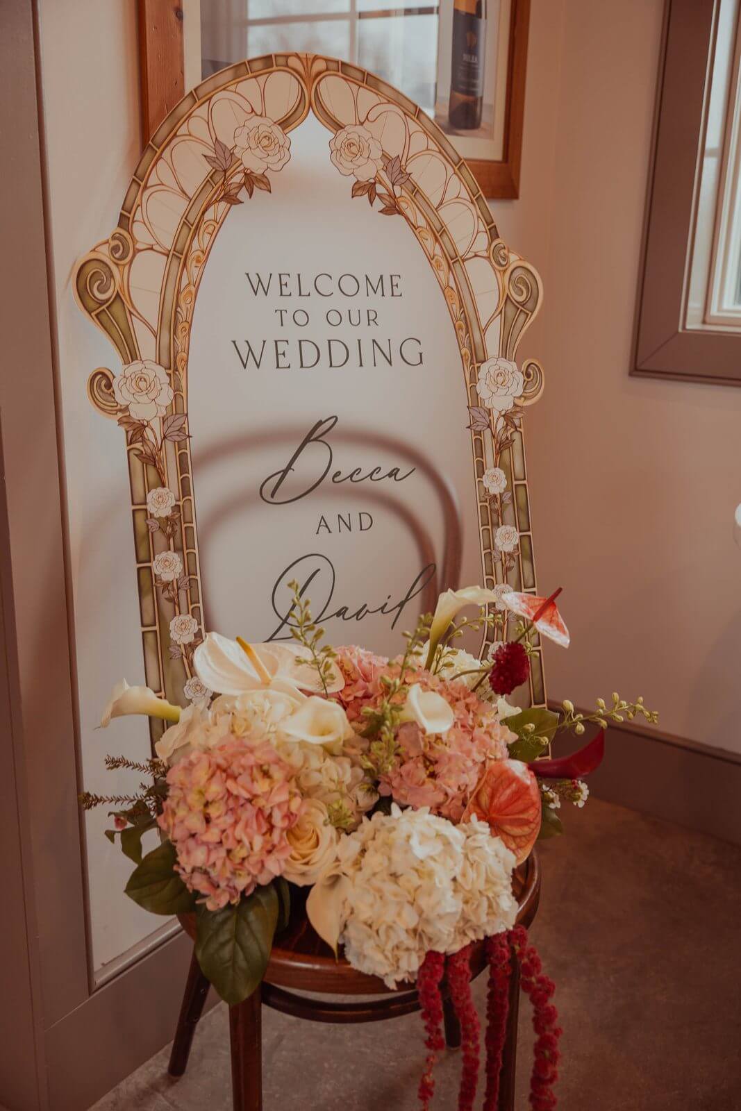Welcome to our wedding sign for Becca and David with a pink and white floral arrangement