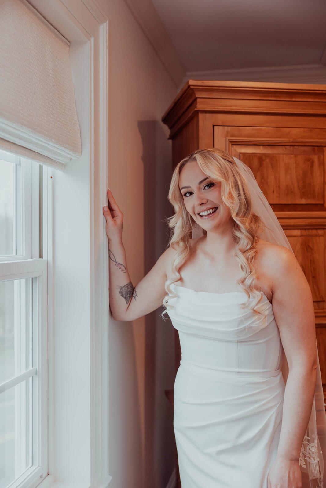 Bride getting ready by a window in the bridal suite at Milea Estate Vineyard